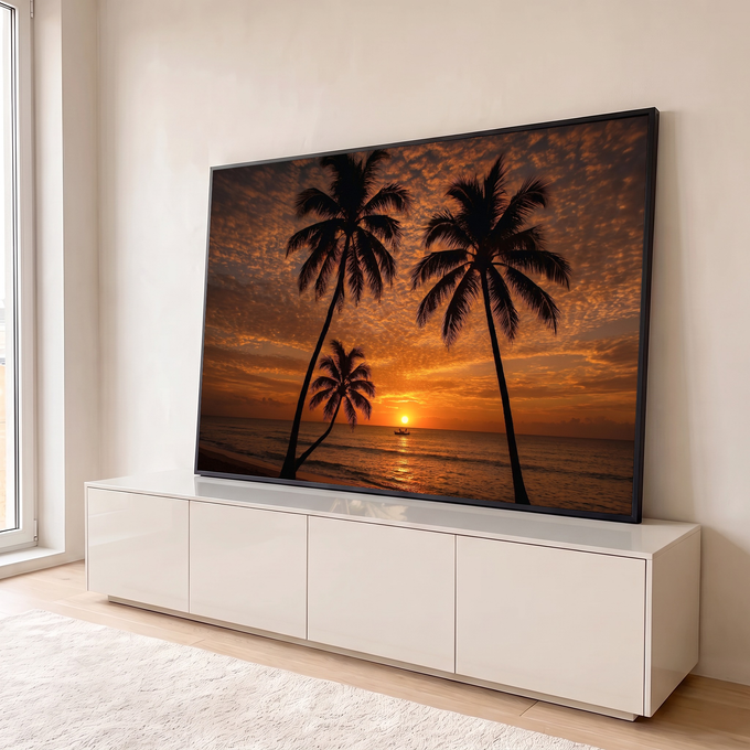 Silhueta de coqueiros na praia com sol se pondo no mar, barco e céu laranja com nuvens, quadro decorativo