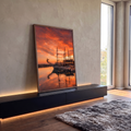 Galeão com mastros refletido na água do porto sob céu laranja de pôr do sol e gaivotas, quadro decorativo