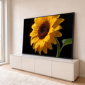 Girassol amarelo em close com gotas de água nas pétalas e folha verde sobre fundo preto, quadro decorativo