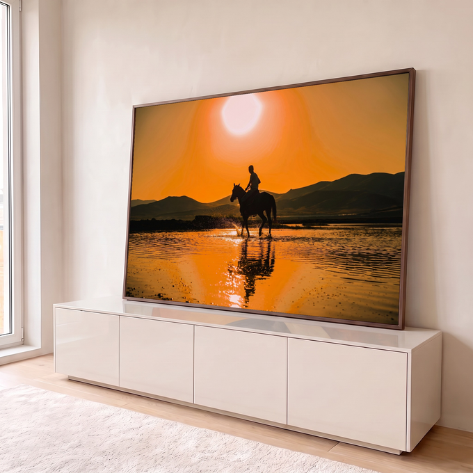 Quadro Decorativo Grande Cavaleiro ao Pôr do Sol para Sala | quadros decorativos para sala | cavaleiro em silhueta atravessando rio raso ao pôr do sol laranja com montanhas ao fundo | em Quadros para Sala | Porao dos Quadros