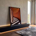Corredor de arcos terracota com faixas de luz e sombra e pessoa caminhando ao fundo, quadro decorativo