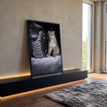 Leopardo-das-neves sentado ao lado de pneu de carro na neve em noite escura, quadro decorativo