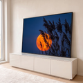 Lua cheia laranja atrás de juncos em silhueta sob céu azul-escuro ao anoitecer, quadro decorativo