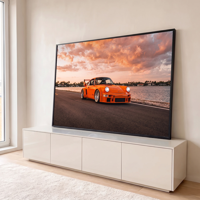 Porsche 911 laranja widebody na estrada à beira d'água sob céu rosado de pôr do sol, quadro decorativo