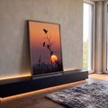 Quatro pássaros em silhueta num galho seco diante do sol se pondo em céu laranja, quadro decorativo