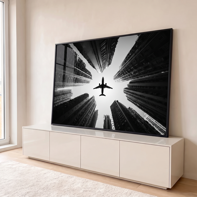 Fotografia preto e branco de avião voando entre arranha-céus vistos de baixo, quadro decorativo