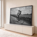 Quadro Decorativo Grande Menino e Cão para Sala Preto | quadros decorativos para sala | menino sorridente pedalando bicicleta com cão em pé no bagageiro, foto preto e branco | em Quadros para Sala | Porao dos Quadros