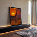 Girafa de pé na savana africana com sol amarelo gigante e céu laranja ao entardecer, quadro decorativo