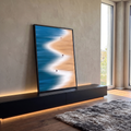 Praia vista do alto com mar azul, espuma branca em zigue-zague e pessoas na areia, quadro decorativo