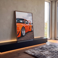 Quadro Decorativo Carro Clássico Laranja com Aerofólio | quadros decorativos para sala | carro esportivo laranja com rodas prateadas e aerofólio em vista lateral baixa | em Quadros para Sala | Porao dos Quadros