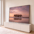 Três rinocerontes caminhando sob céu rosa ao pôr do sol, refletidos na água calma, quadro decorativo