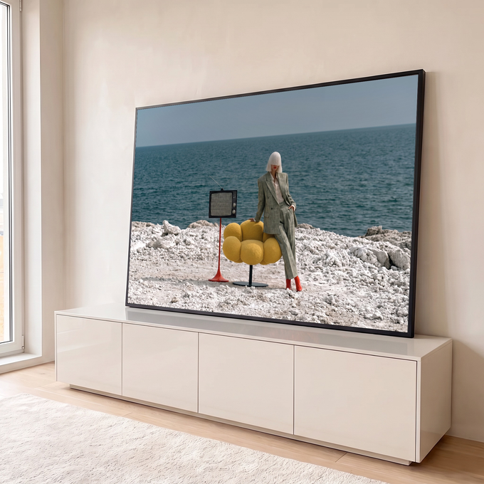 Mulher de terno xadrez e botas vermelhas com TV retrô e poltrona amarela à beira-mar, quadro decorativo