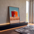 Garça-cinzenta em campo de grama dourada com silo laranja e céu azul ao fundo, quadro decorativo