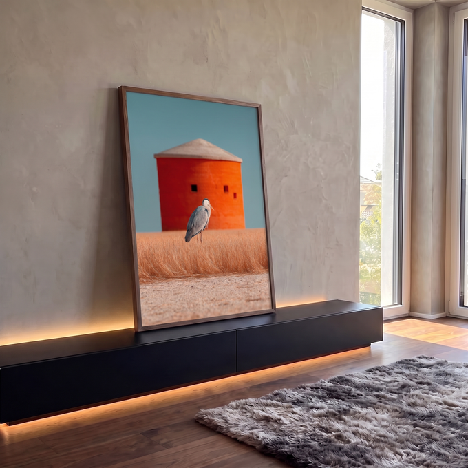 Garça-cinzenta em campo de grama dourada com silo laranja e céu azul ao fundo, quadro decorativo