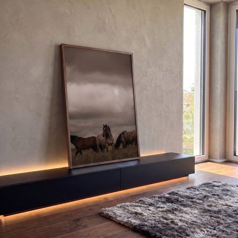 Três cavalos em campo aberto sob céu nublado cinza, fotografia em tons terrosos, quadro decorativo