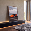 Quadro Decorativo Grande Carro Clássico para Sala Laranja | quadros decorativos para sala | carro esportivo laranja com aerofólio à beira da água e skyline ao fundo | em Quadros para Sala | Porao dos Quadros