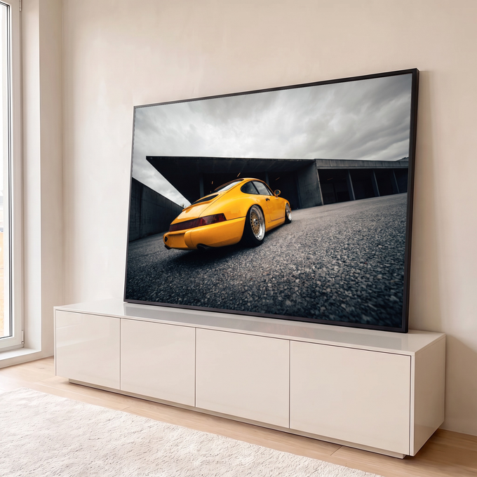 Porsche 911 amarelo visto de trás com rodas douradas sob céu nublado e concreto, quadro decorativo