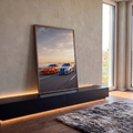 Toyota Supra laranja e Nissan GT-R R34 prata em estrada à beira-mar ao pôr do sol, quadro decorativo