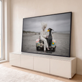 Quadro Decorativo Grande Mulher e Ave para Sala Branco | quadros decorativos para sala | mulher de terno branco ao lado de ave surreal de óculos sobre carro antigo na praia | em Quadros para Sala | Porao dos Quadros