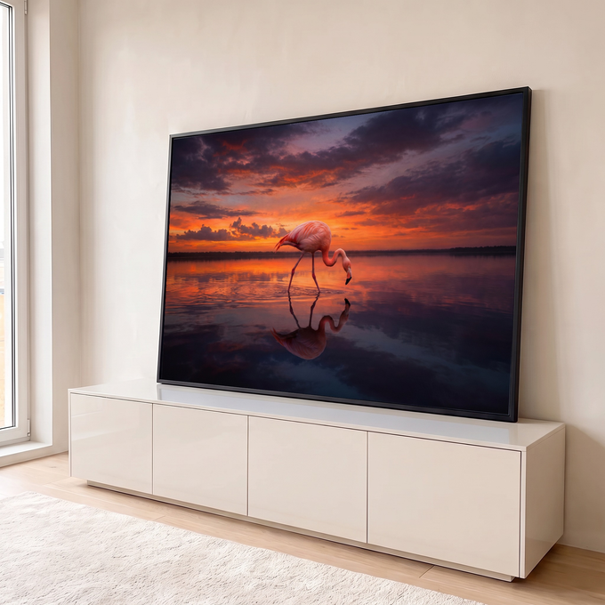 Flamingo rosa caminhando em lago calmo com reflexo na água sob céu laranja de pôr do sol, quadro decorativo