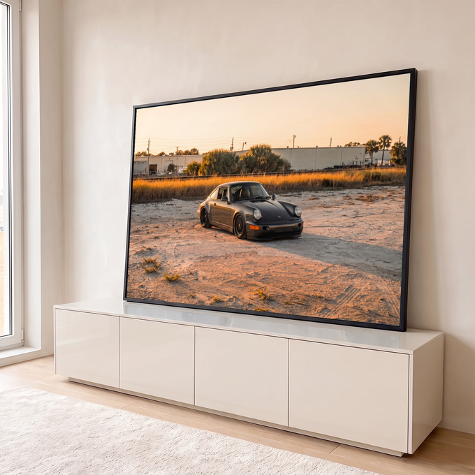 Porsche 911 clássico cinza rebaixado sobre areia com capim dourado e palmeiras ao pôr do sol, quadro decorativo