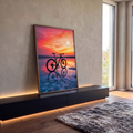Mountain bike em silhueta refletida em salina sob pôr do sol rosa e laranja com pássaros, quadro decorativo
