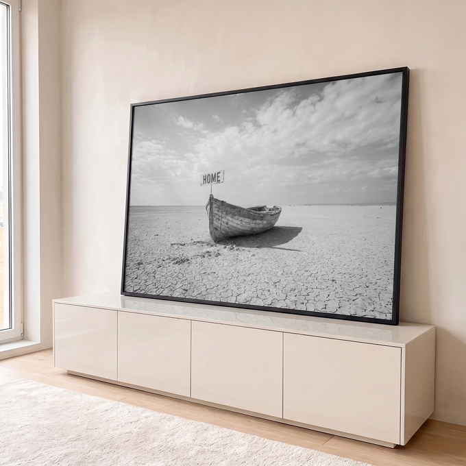 Barco de madeira antigo em terra seca e rachada com placa HOME sob céu nublado, em preto e branco, quadro decorativo