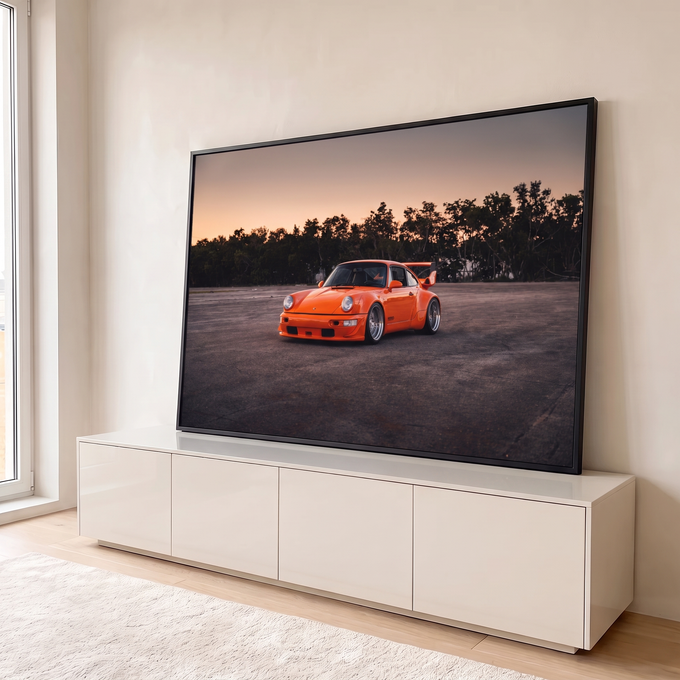Porsche 911 RWB laranja com aerofólio em pátio de asfalto ao entardecer, árvores ao fundo, quadro decorativo