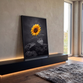 Girassol amarelo brotando entre pedras vulcânicas pretas em fundo cinza escuro, quadro decorativo