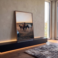 Cavalos marrom, malhado e potro no campo ao pôr do sol, com carro esportivo no canto, quadro decorativo