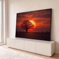 Árvore em silhueta diante de sol gigante, pássaros em voo e céu laranja no campo, quadro decorativo