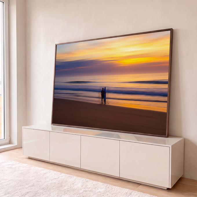 Silhueta de surfista com prancha azul na areia diante do mar ao pôr do sol laranja, quadro decorativo