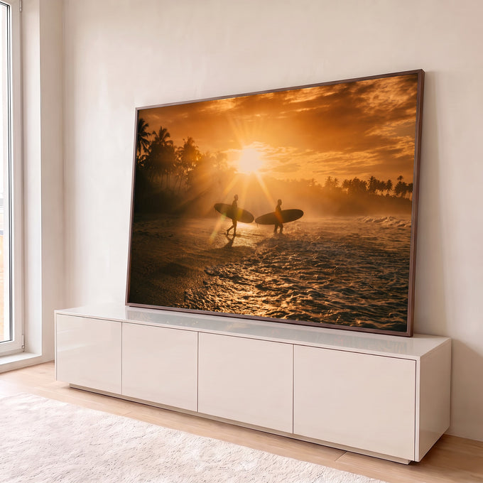 Dois surfistas em silhueta com pranchas entrando no mar ao pôr do sol entre palmeiras, quadro decorativo