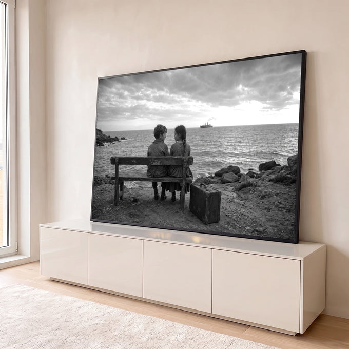 Fotografia P&B de duas crianças em banco de madeira à beira-mar olhando navio ao longe, quadro decorativo