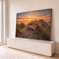 Barco de madeira antigo entre a vegetação da duna, praia e mar ao pôr do sol laranja, quadro decorativo