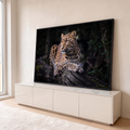 Leopardo deitado sobre tronco com musgo olhando para o lado em fundo escuro de floresta, quadro decorativo