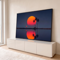 Sol laranja gigante refletido na água com flamingo, barco e palmeiras em céu azul, quadro decorativo