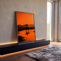 Silhueta de cavaleiro atravessando água com reflexo, montanhas e céu laranja ao pôr do sol, quadro decorativo