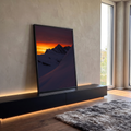 Pico nevado em silhueta contra céu laranja ao pôr do sol, encosta de neve em sombra, quadro decorativo