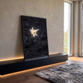 Lírio branco solitário iluminado sobre solo de pedras vulcânicas escuras, quadro decorativo