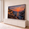 Dois gatos num muro de pedra olhando o pôr do sol laranja sobre o mar, penhascos e vilarejo, quadro decorativo