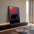 Elefante africano em silhueta contra céu roxo e laranja do pôr do sol à beira do rio, quadro decorativo