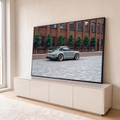 Porsche 911 clássico cinza com rodas douradas em rua de paralelepípedos e prédio de tijolos, quadro decorativo