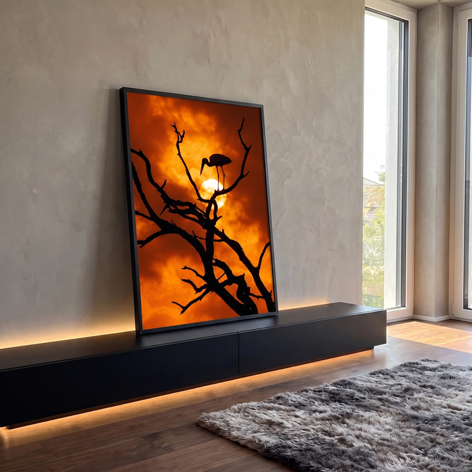Silhueta de cegonha em galho seco diante do sol e céu laranja ao entardecer, quadro decorativo
