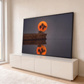 Quadro Decorativo Grande Lua com Palmeiras para Sala Laranja | quadros decorativos para sala | lua laranja gigante atrás de palmeiras e cabana de barro sobre penhasco refletido na água | em Quadros para Sala | Porao dos Quadros