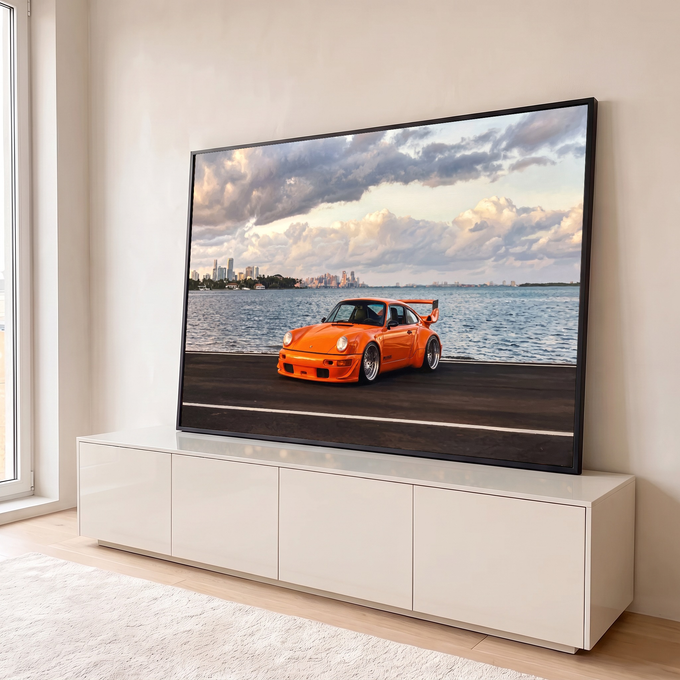 Porsche 911 laranja com aerofólio na orla, mar e skyline sob nuvens ao entardecer, quadro decorativo