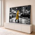 Pessoa de capa amarela atravessando rua chuvosa com táxis em cena preto e branco, quadro decorativo