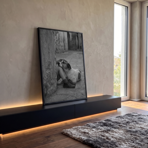 Cachorro apoiado nos joelhos de criança em beco de pedra, foto em preto e branco, quadro decorativo