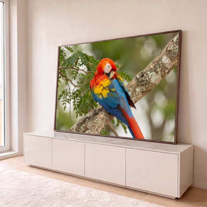 Arara-vermelha ajeitando as penas num tronco com folhagem verde desfocada ao fundo, quadro decorativo