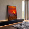 Girafa em pé na savana africana com acácias diante de sol gigante e céu vermelho, quadro decorativo